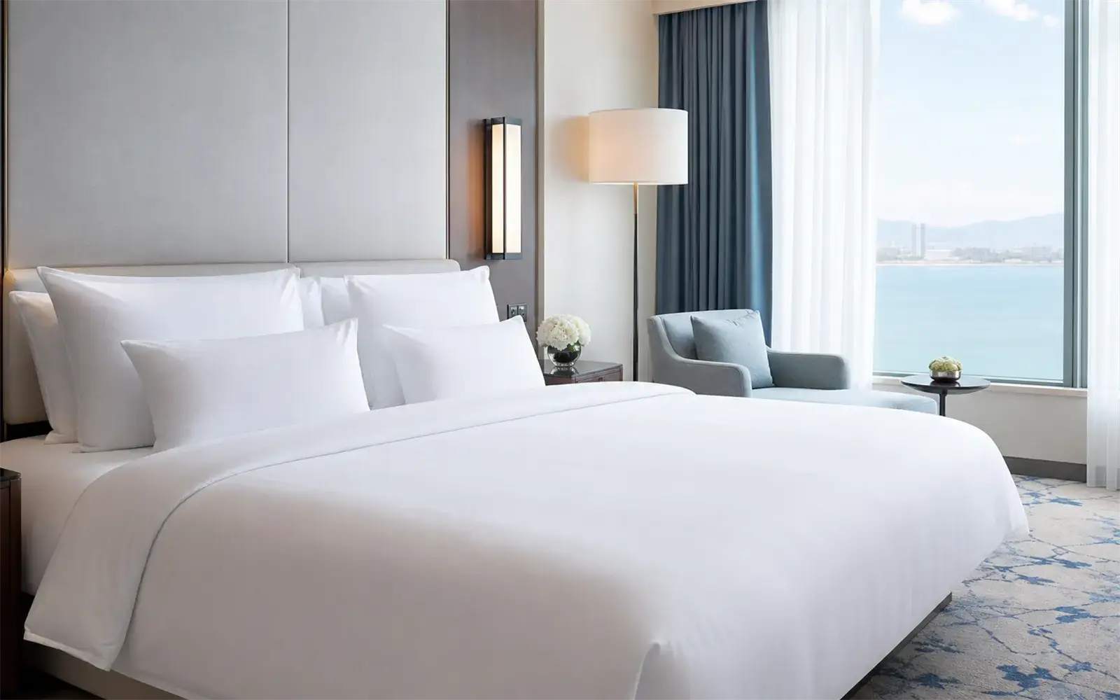 Frisch bezogenes Hotelbett mit weißer Bettwäsche in einem hellen Hotelzimmer